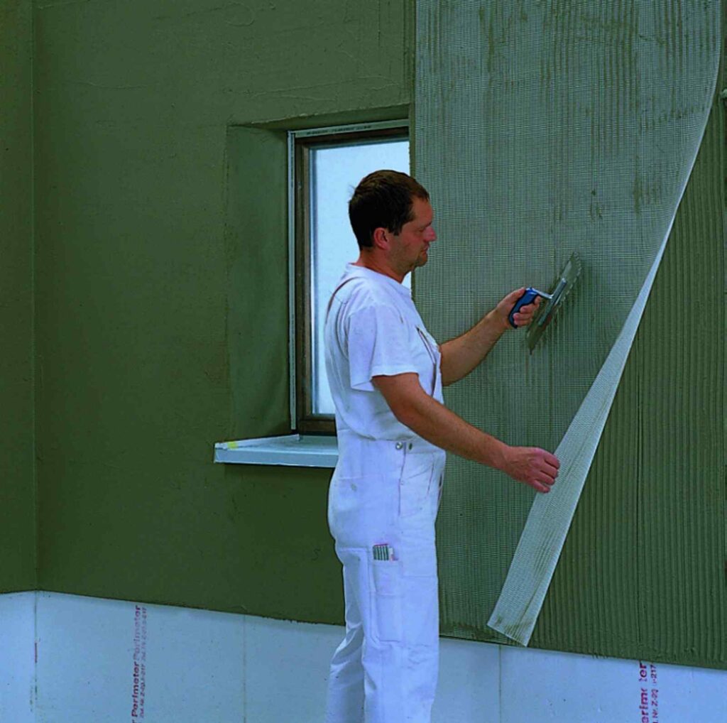 Nanoszenie zaprawy klejowej i zatapianie w niej siatki z wlokma szklanego, fot. Baumit